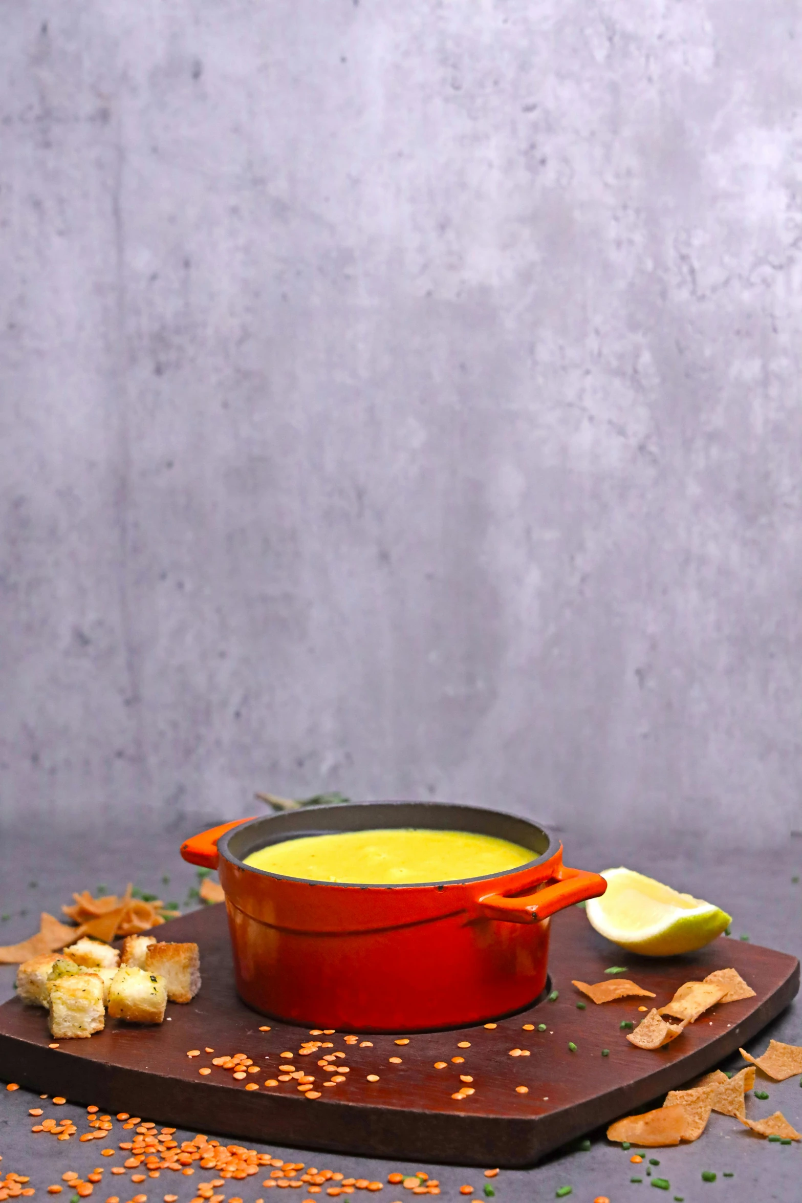 a pot of soup next to some snacks on a wooden platter