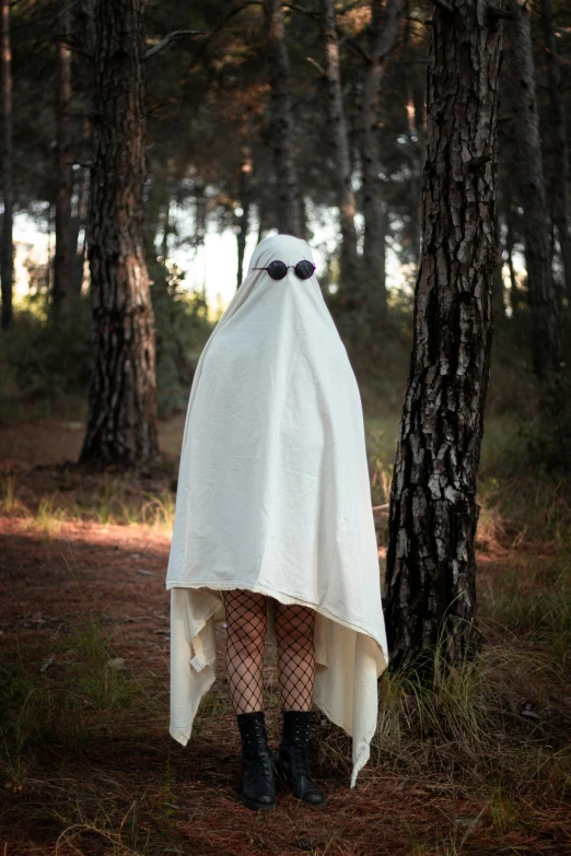 a ghostly woman with black eyes hiding behind a blanket in the woods