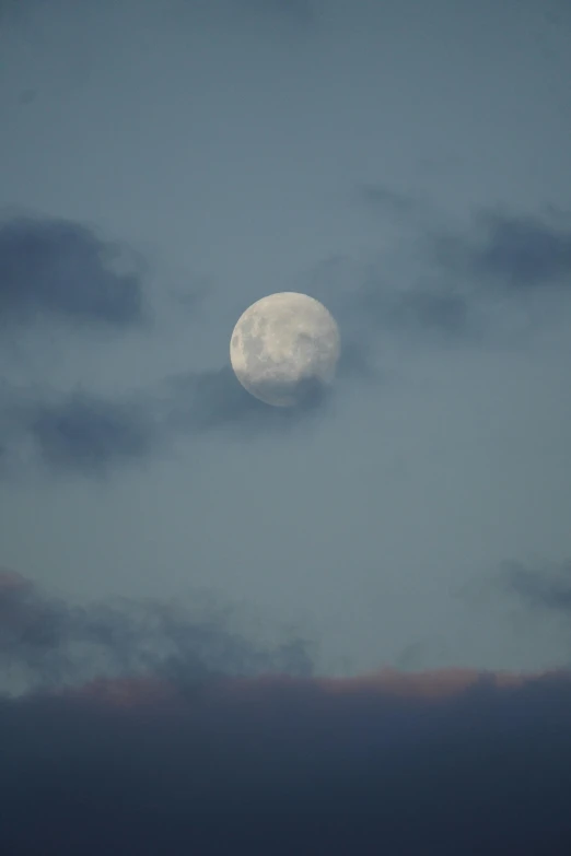 a full moon and clouds in a blue sky