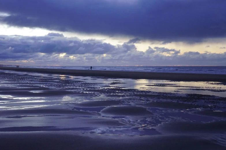 a person is walking alone on the beach with an umbrella