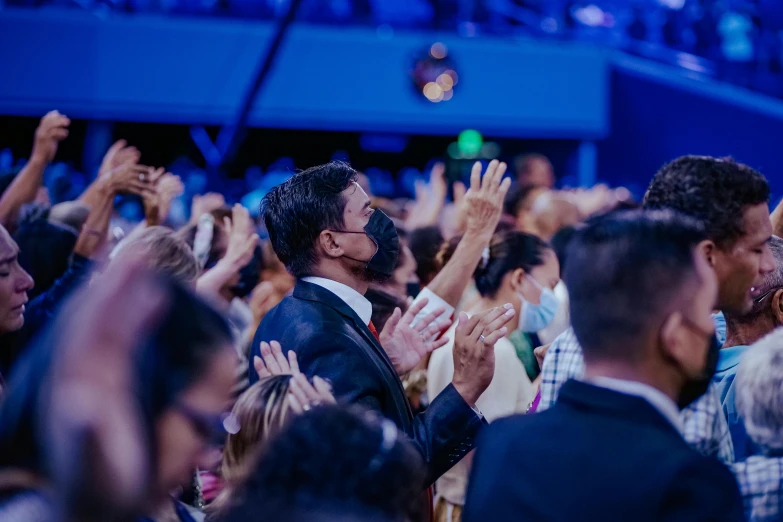 a crowd of people clapping and having their hands up