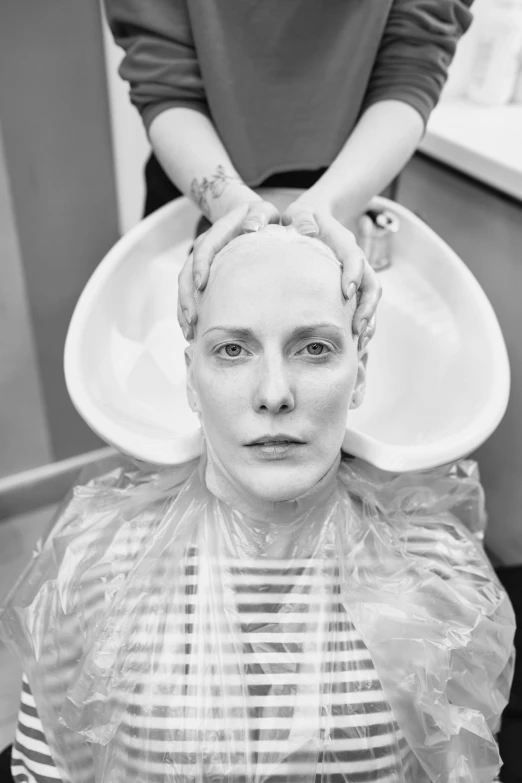 a woman's head covered in plastic is shown as she sits at a salon