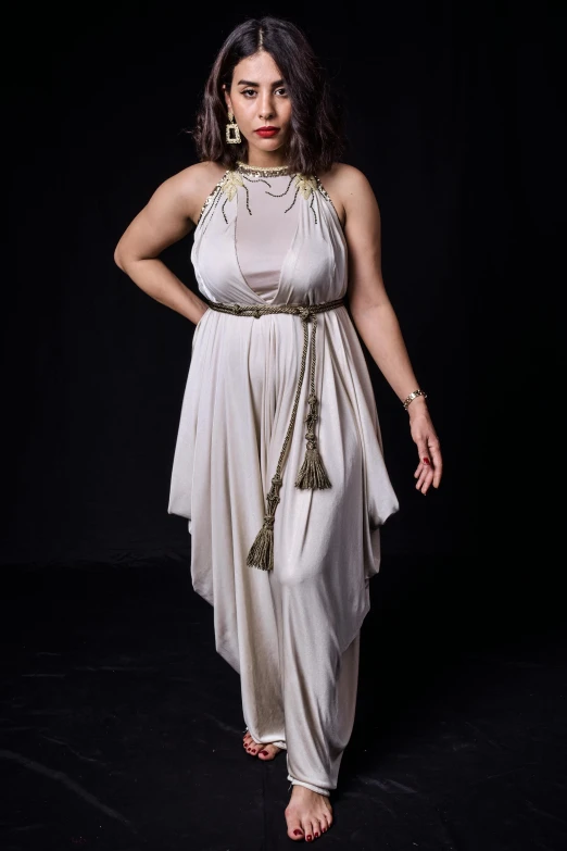 woman in cream dress posing for camera on black background