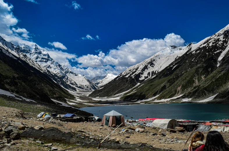 a group of tents pitched up in front of snow covered mountains