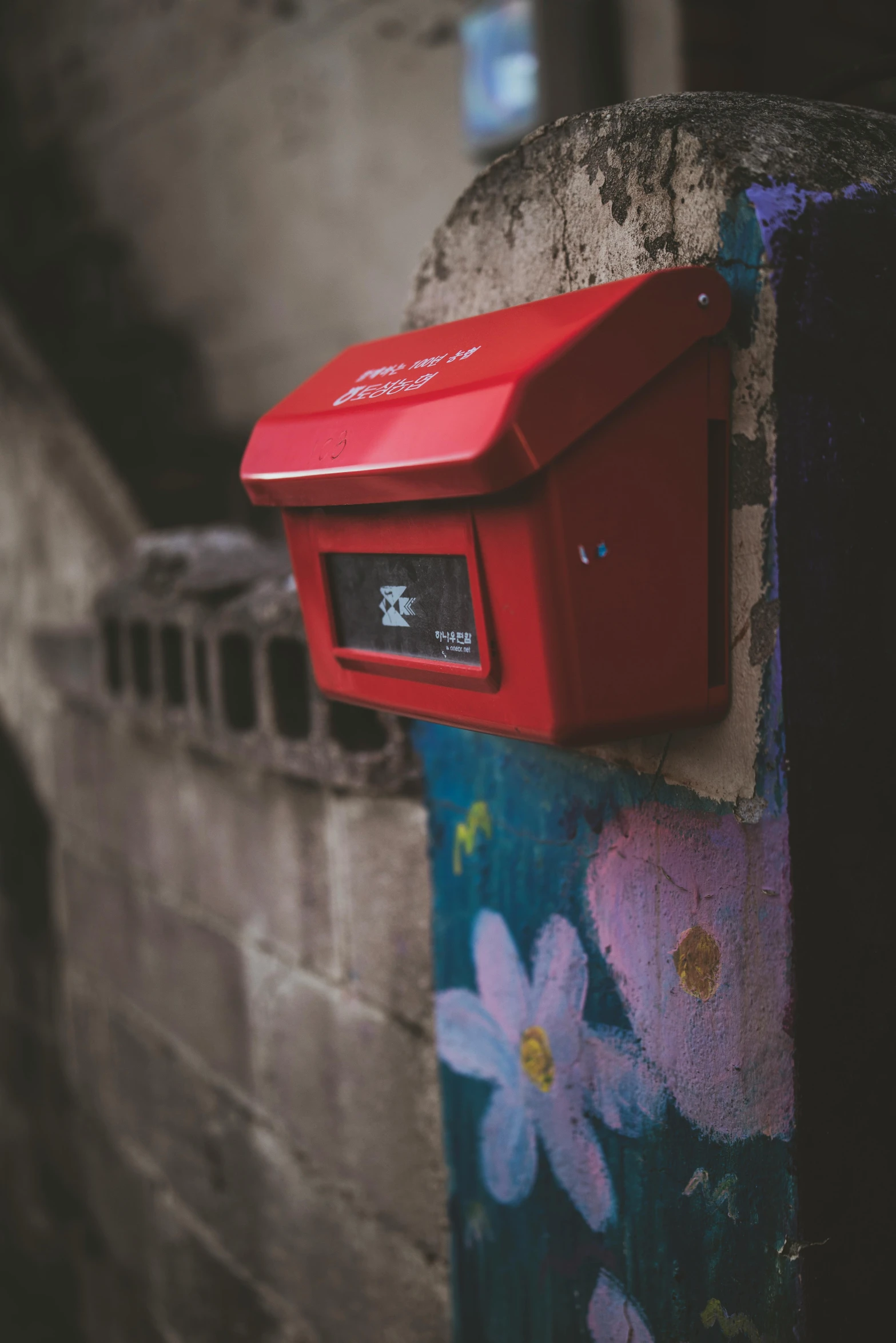 a red mail box with flowers and birds painted on it