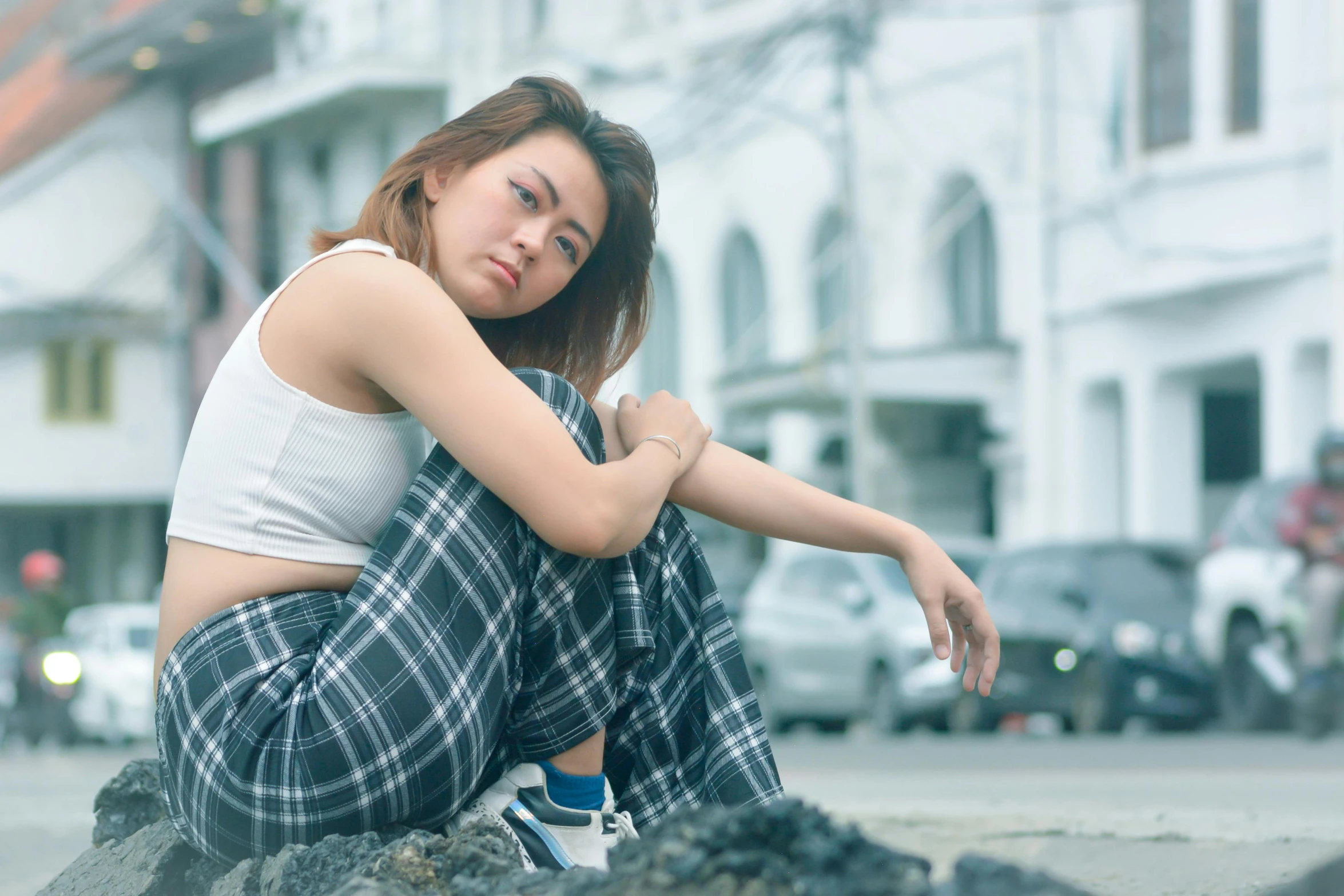 a beautiful woman sitting on the ground in a white shirt