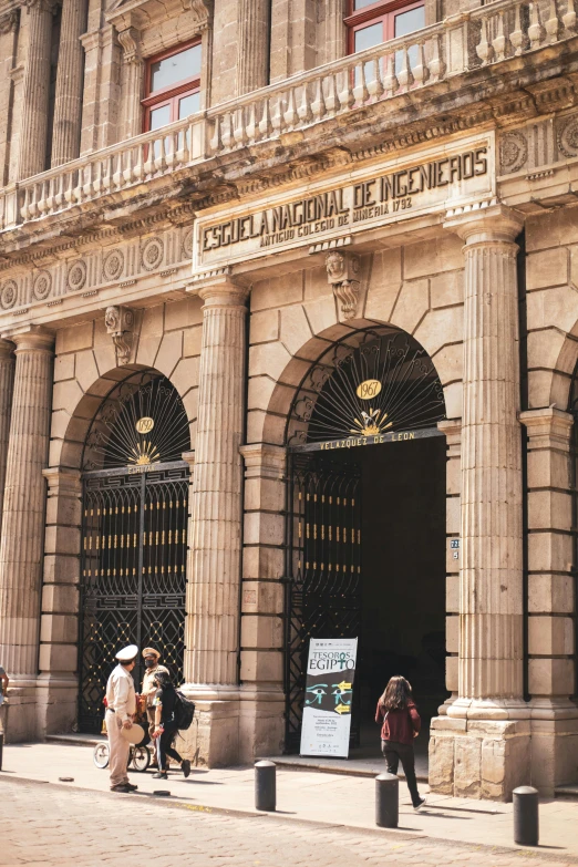 an old building with arched doors, pillars and people in front