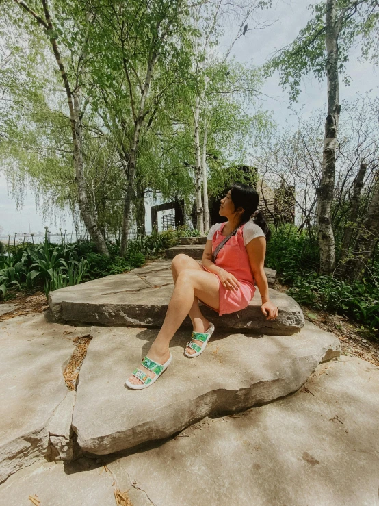 a woman wearing sandals sitting on rocks near water