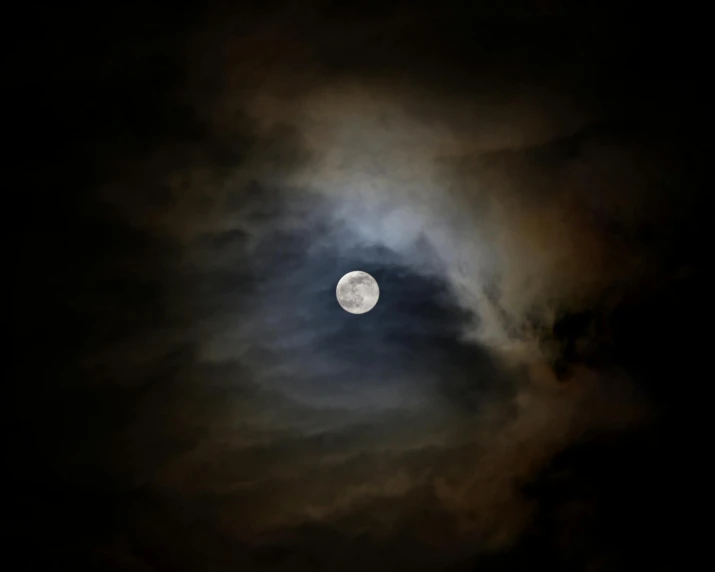 the moon seen through clouds in the dark sky