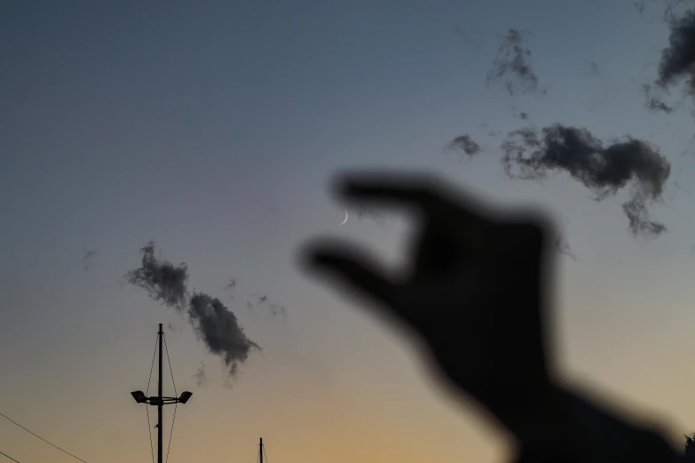 a person is silhouetted against the sky and has a hand showing in front of him