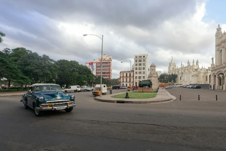 an old blue car is in the middle of a road