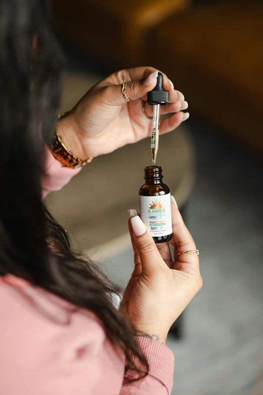 a person holding a glass bottle of essential oils