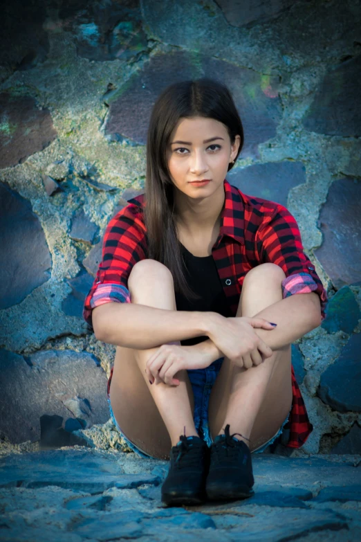 a woman crouching down next to a wall