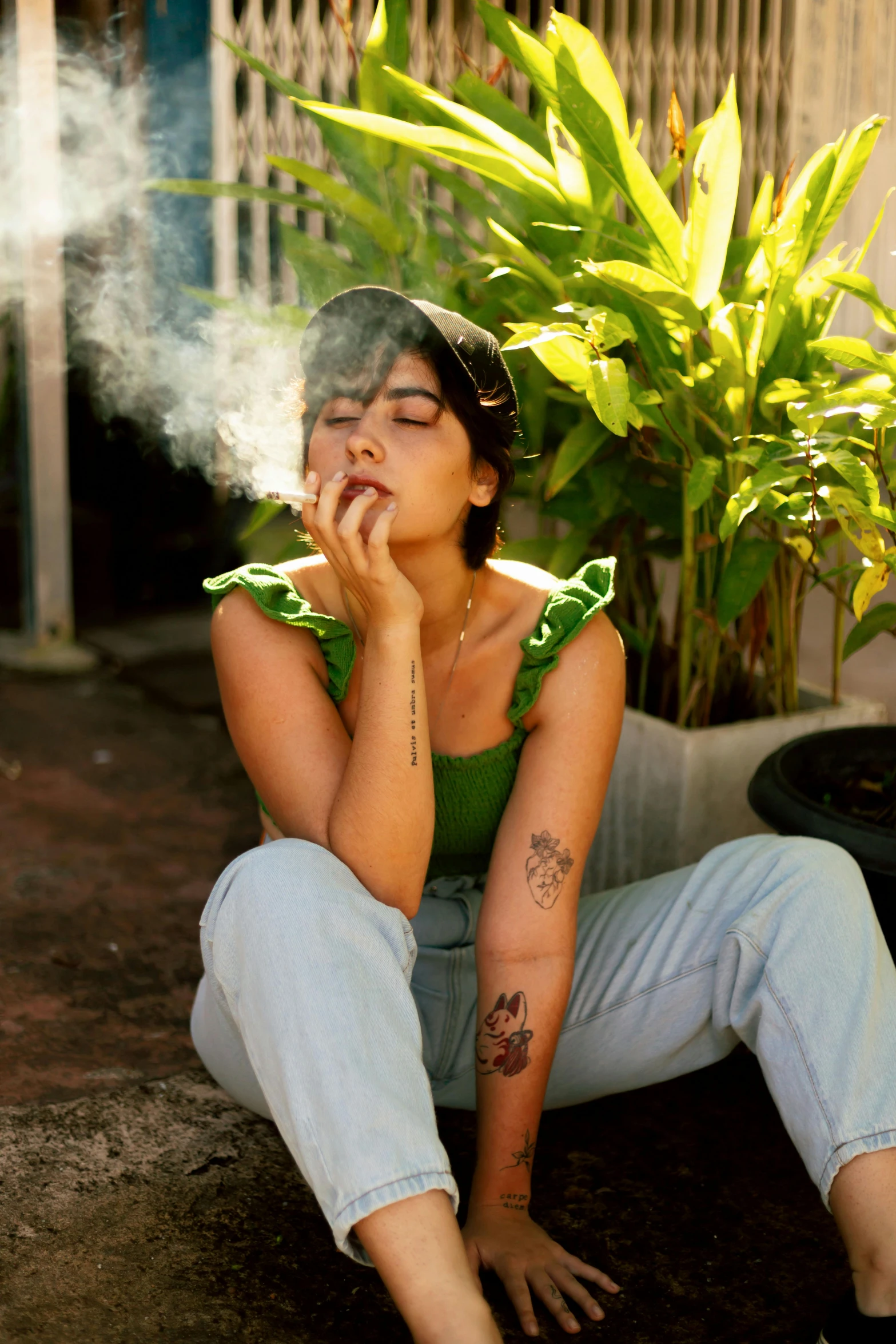 the woman smokes a cigarette outside near a potted plant