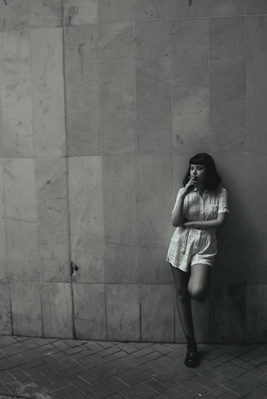 a girl standing next to a wall while covering her face