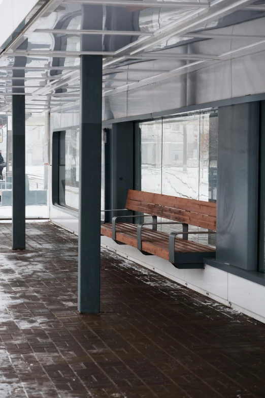 an empty public space with wooden benches and windows in it