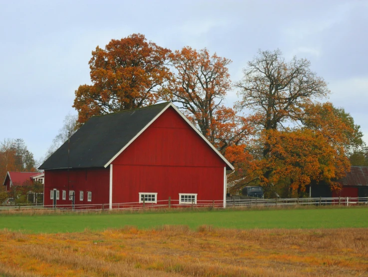 an image of a red farm with barn and trees