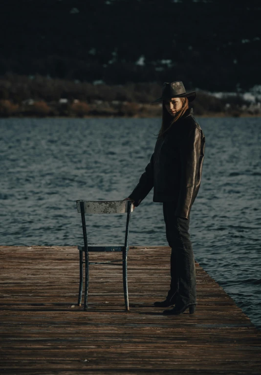 a woman poses with her chair by the edge of the water