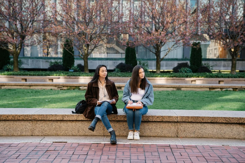 two women are sitting on a bench at a park