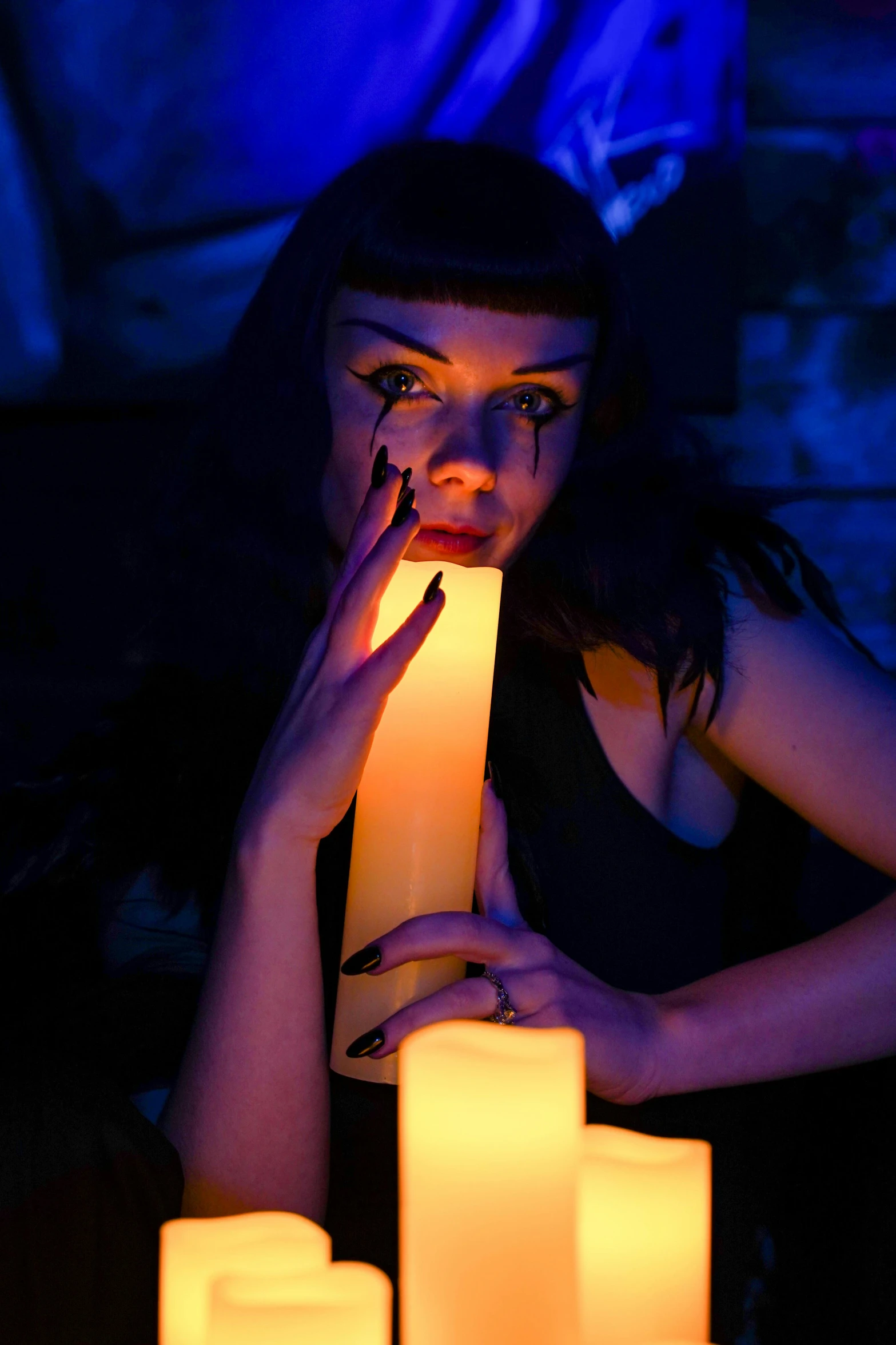 a woman sitting at a table holding a lit candle