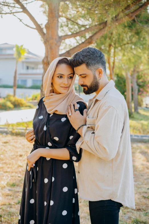 an attractive couple emce while standing under a tree