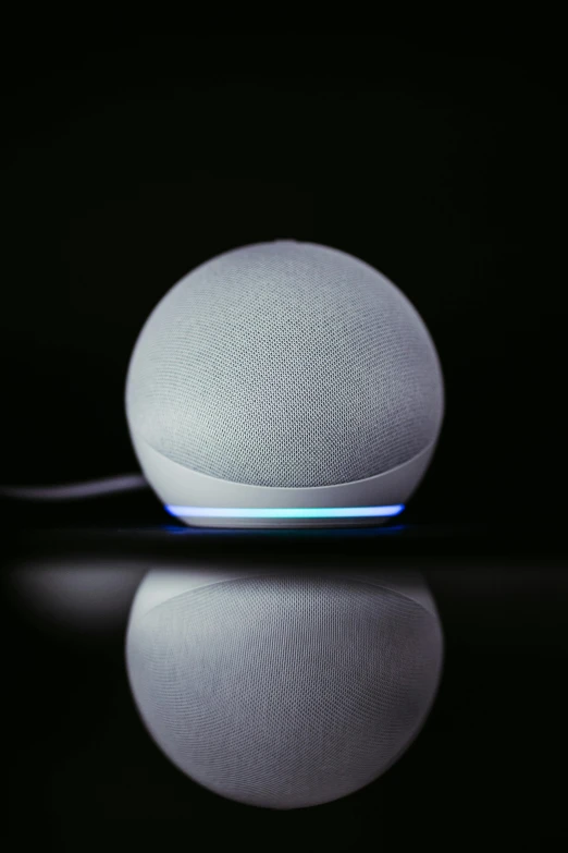 a white sphere like device sits on top of a reflective surface
