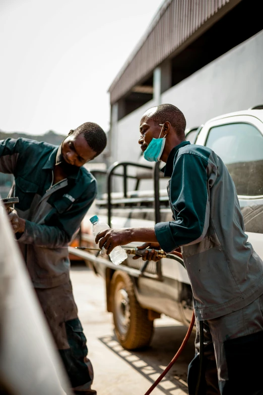 two men washing and using hoses in front of a white truck