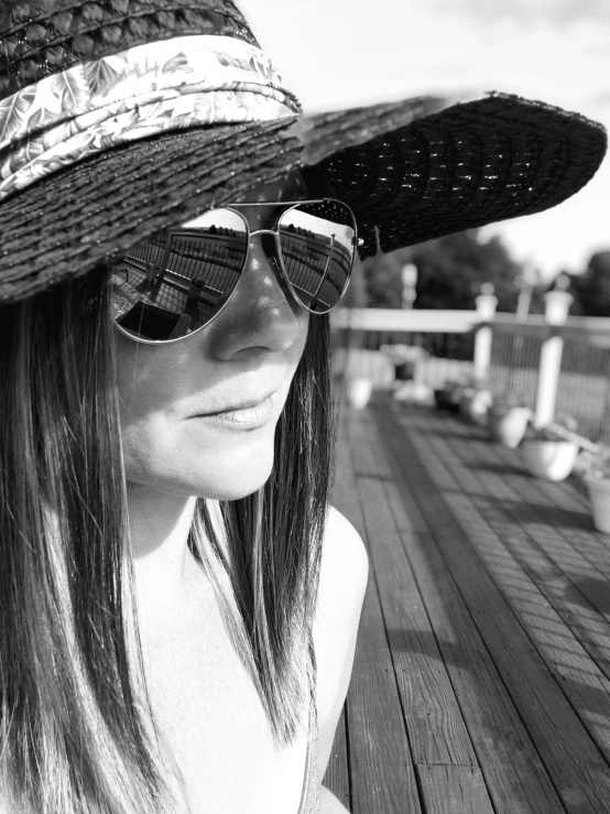 a woman wearing sunglasses and hat standing by some benches