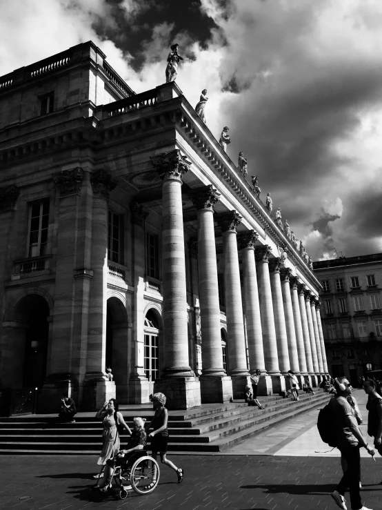 two people standing near large pillared building under clouds