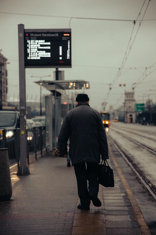 person in coat walking with a suitcase in rain