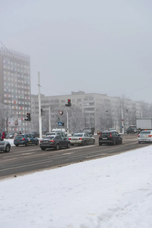 snow covered cars drive through a snow covered city