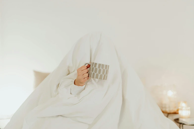 a woman sitting on a bed holding a mug