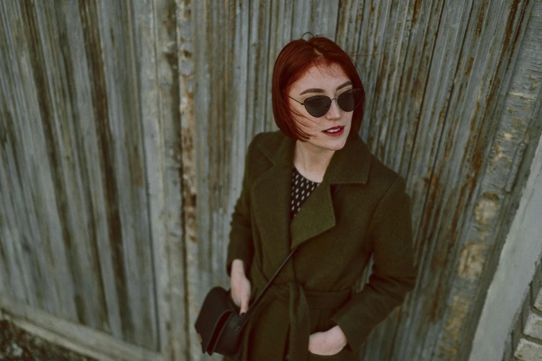 a woman in sunglasses is wearing glasses near a fence