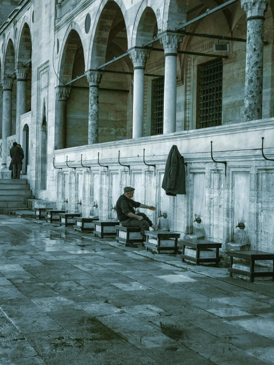 a person sitting on a bench near the wall of a building