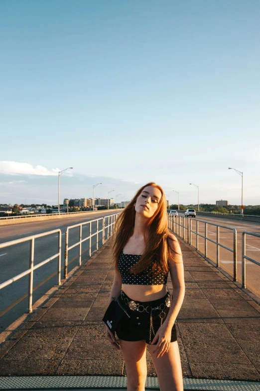 a woman with short shorts and boots standing by the side of a bridge