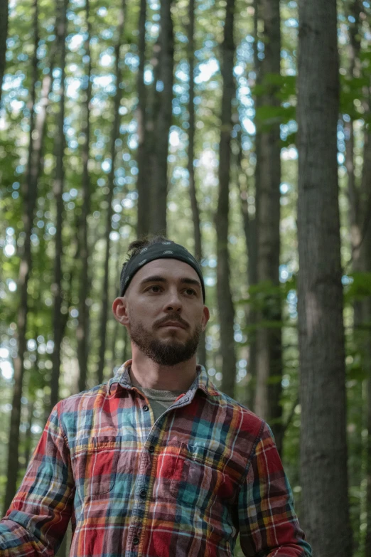 the bearded man stands in the middle of the forest