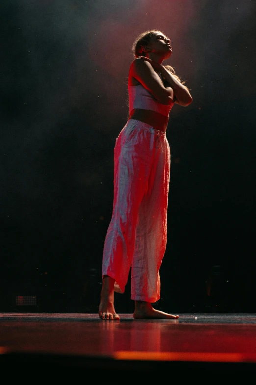 the woman is standing on stage with her arms clasped