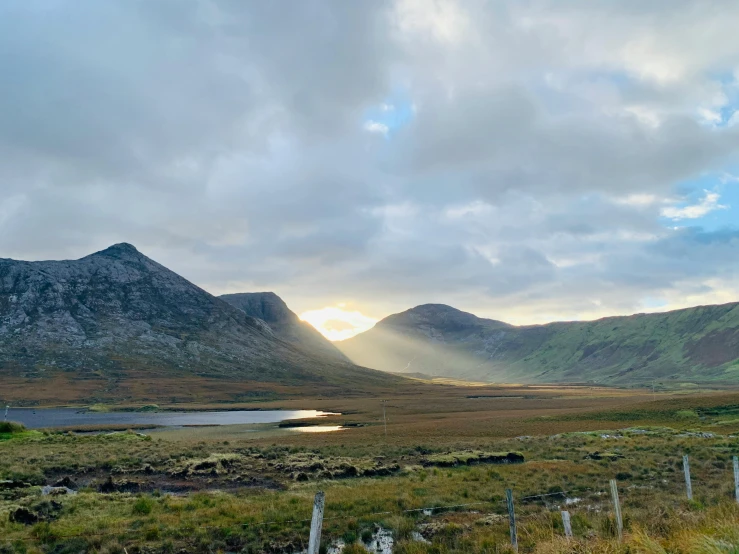 a small lake near some mountains under cloudy skies