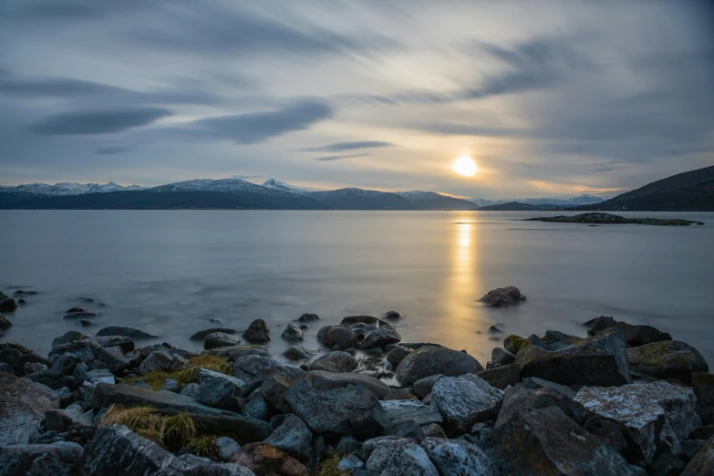 a lake full of rocks near some mountains