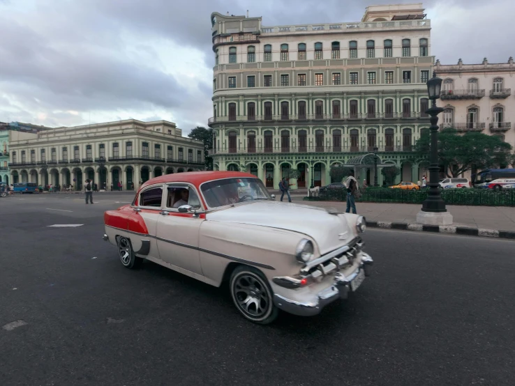 a vintage white car is driving down the road