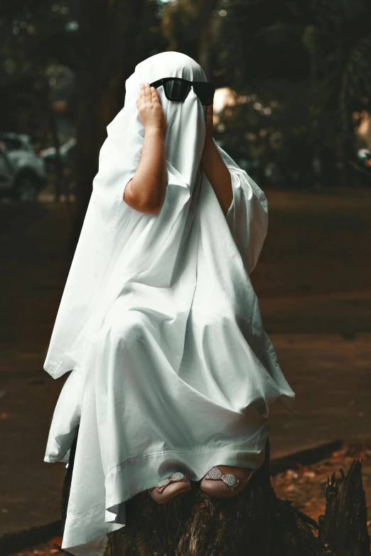 the veiled woman in the white outfit is covering her face with an umbrella