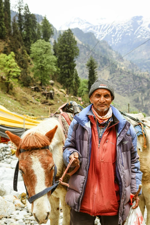 man standing on rocks holding a small pony