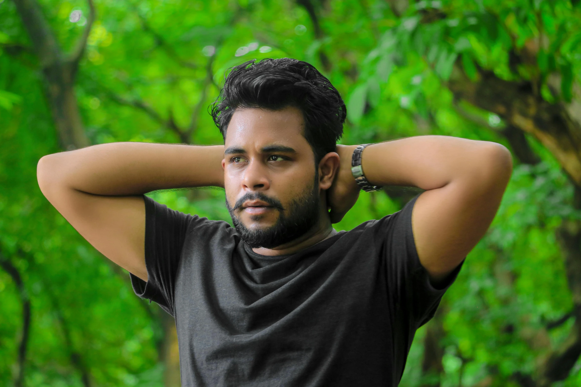 a bearded man is posing in front of some trees