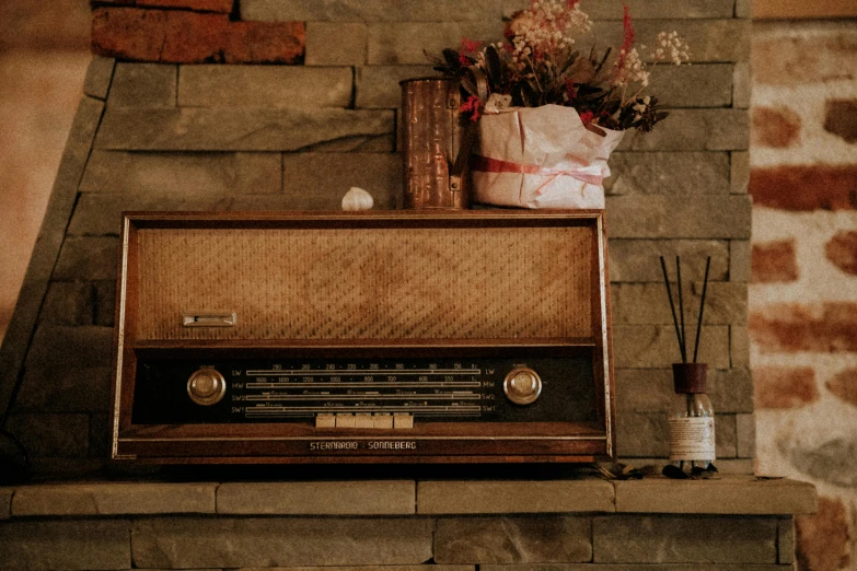 an old fashion radio sits on the mantle with some flowers