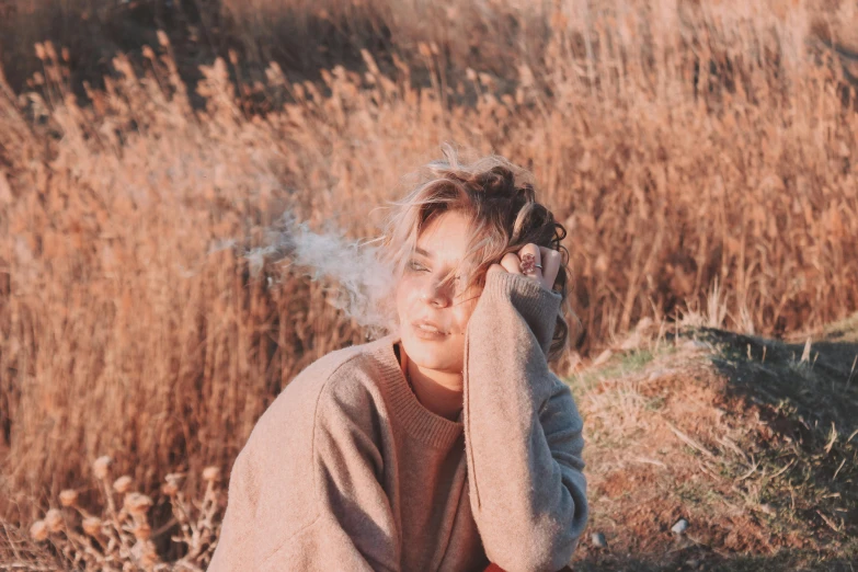 a woman with her eyes closed sitting in the grass, smoke coming from her ears