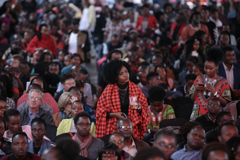 a large crowd is watching an event that has a woman standing in the middle of the crowd