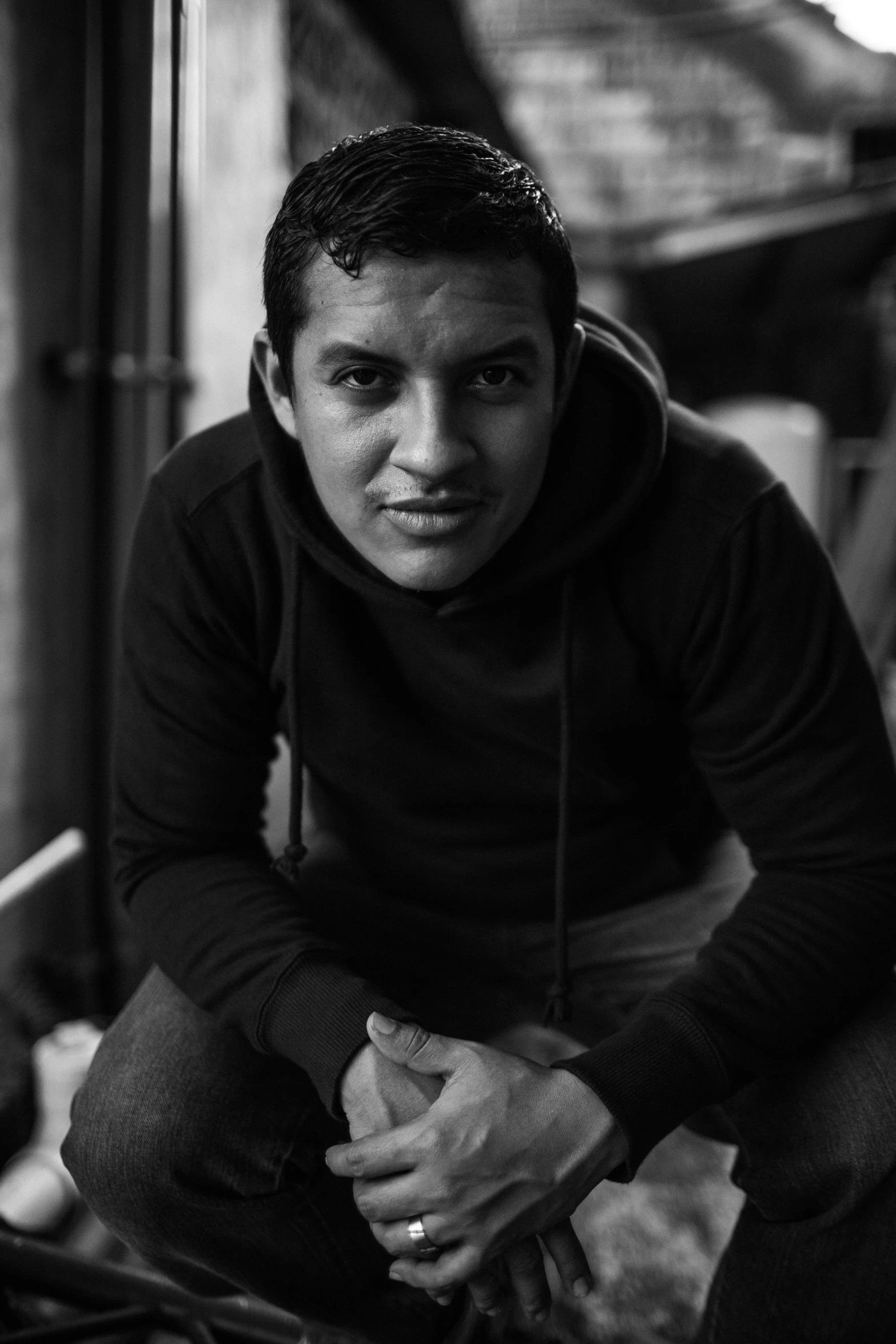 black and white image of man crouched down wearing sweater