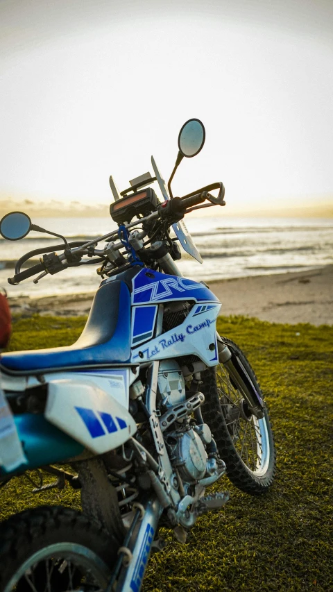 a blue and white dirt bike parked near the ocean