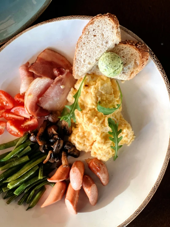 the plate is full of eggs, bacon, asparagus, tomatoes and toast
