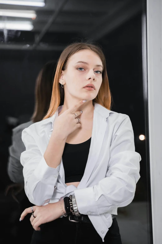 a woman in a white blazer and jeans with a cigarette on her hand